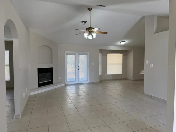 a view of a livingroom with a fireplace a chandelier and windows