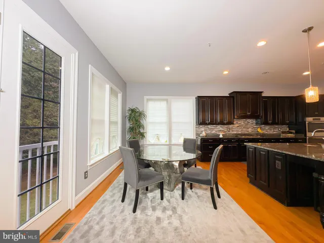 a dining room with stainless steel appliances a dining table chairs and a white refrigerator with a large window