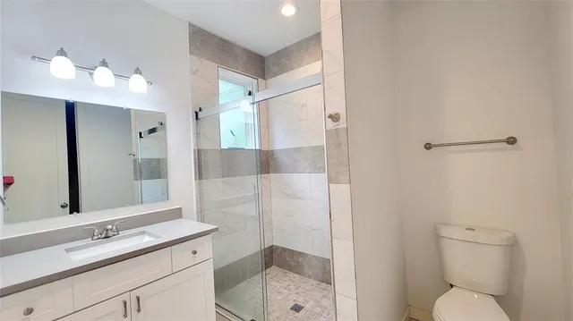 a bathroom with a shower sink vanity mirror and toilet