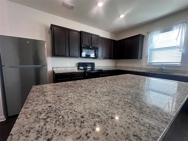 a kitchen with kitchen island a refrigerator sink and wooden cabinets