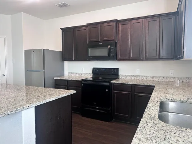 a kitchen with granite countertop a refrigerator and a sink