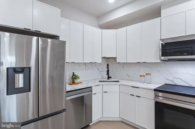 a kitchen with stainless steel appliances white cabinets and a refrigerator