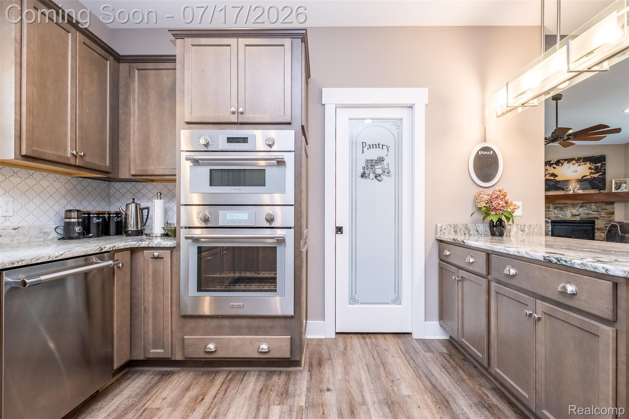 12349 Sugar Maple Drive Fenton, MI 48430 - Photo 18 of 67 Kitchen featuring light wood-finish cabinetry, stainless steel double ovens, and a dedicated pantry with a frosted glass door