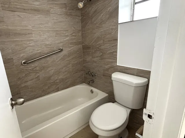 a white toilet sitting next to a bath tub