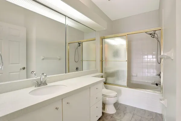 a bathroom with a granite countertop sink toilet and shower