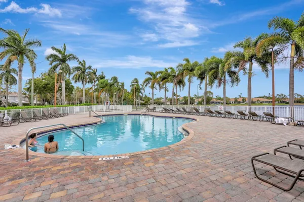 a view of swimming pool with outdoor seating and palm trees