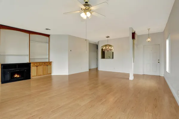 a view of an empty room with a fireplace and a chandelier fan
