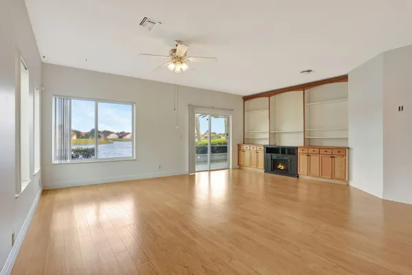a view of an empty room with window and wooden floor