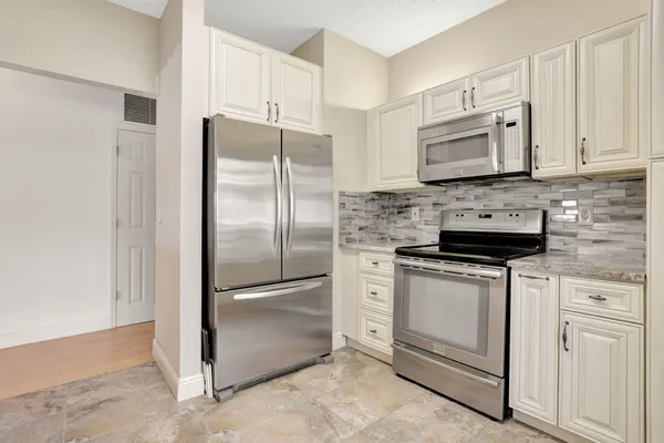 a kitchen with white cabinets and stainless steel appliances
