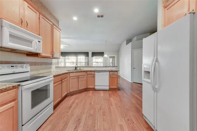 a large kitchen with a wooden floor and stainless steel appliances