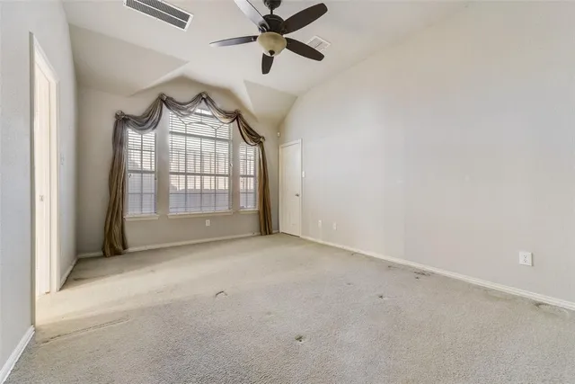 an empty room with windows and fan