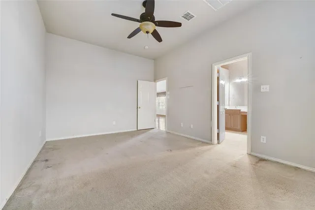 an empty room with chandelier fan and windows