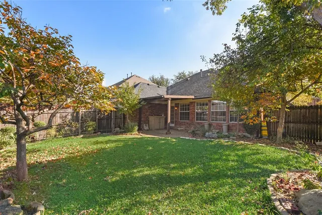 a view of a yard in front of a house with a large tree
