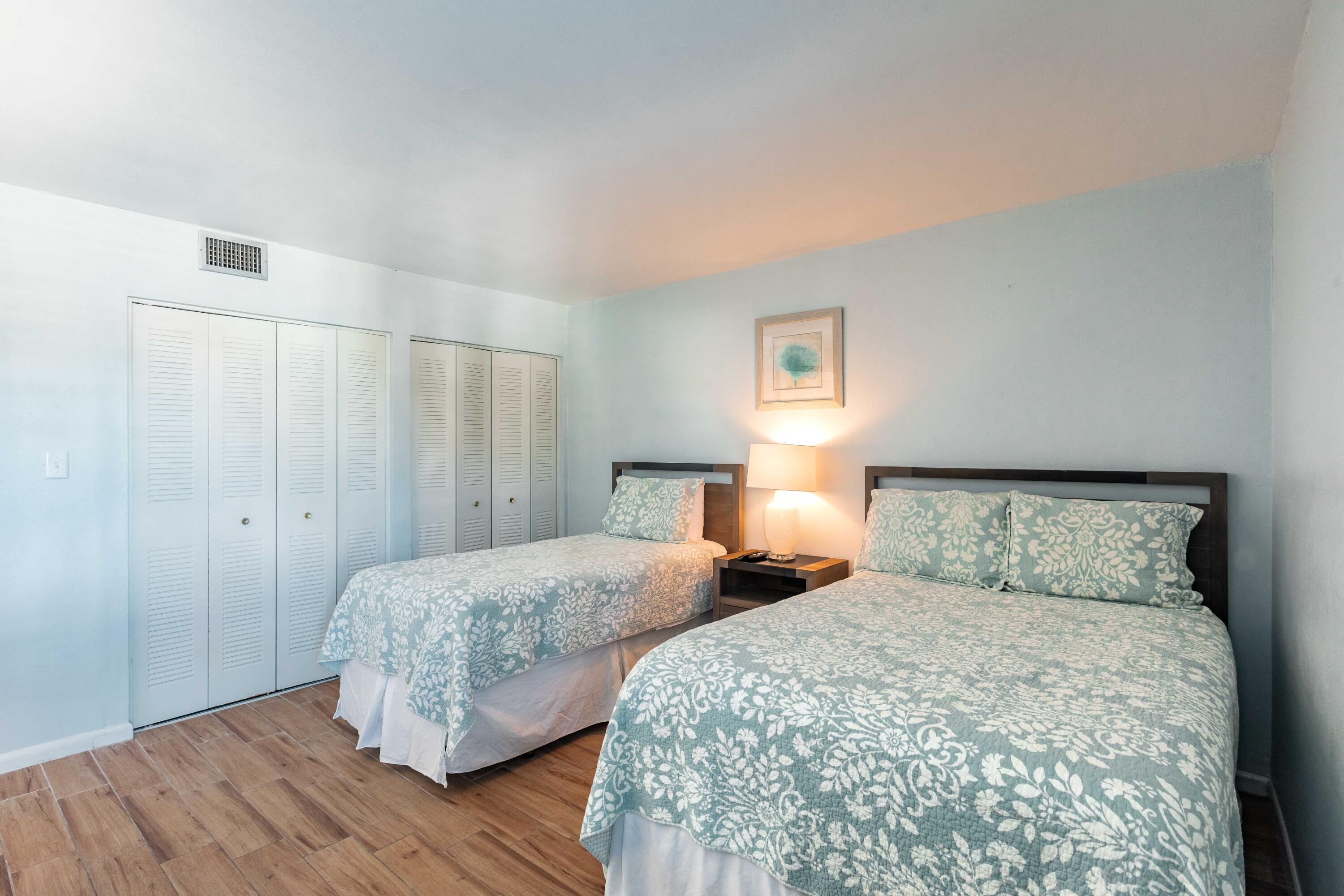 1030 East E Highway, Unit 25 Destin, FL 32541 - Photo 16 of 34 a bedroom with two beds and wooden floor