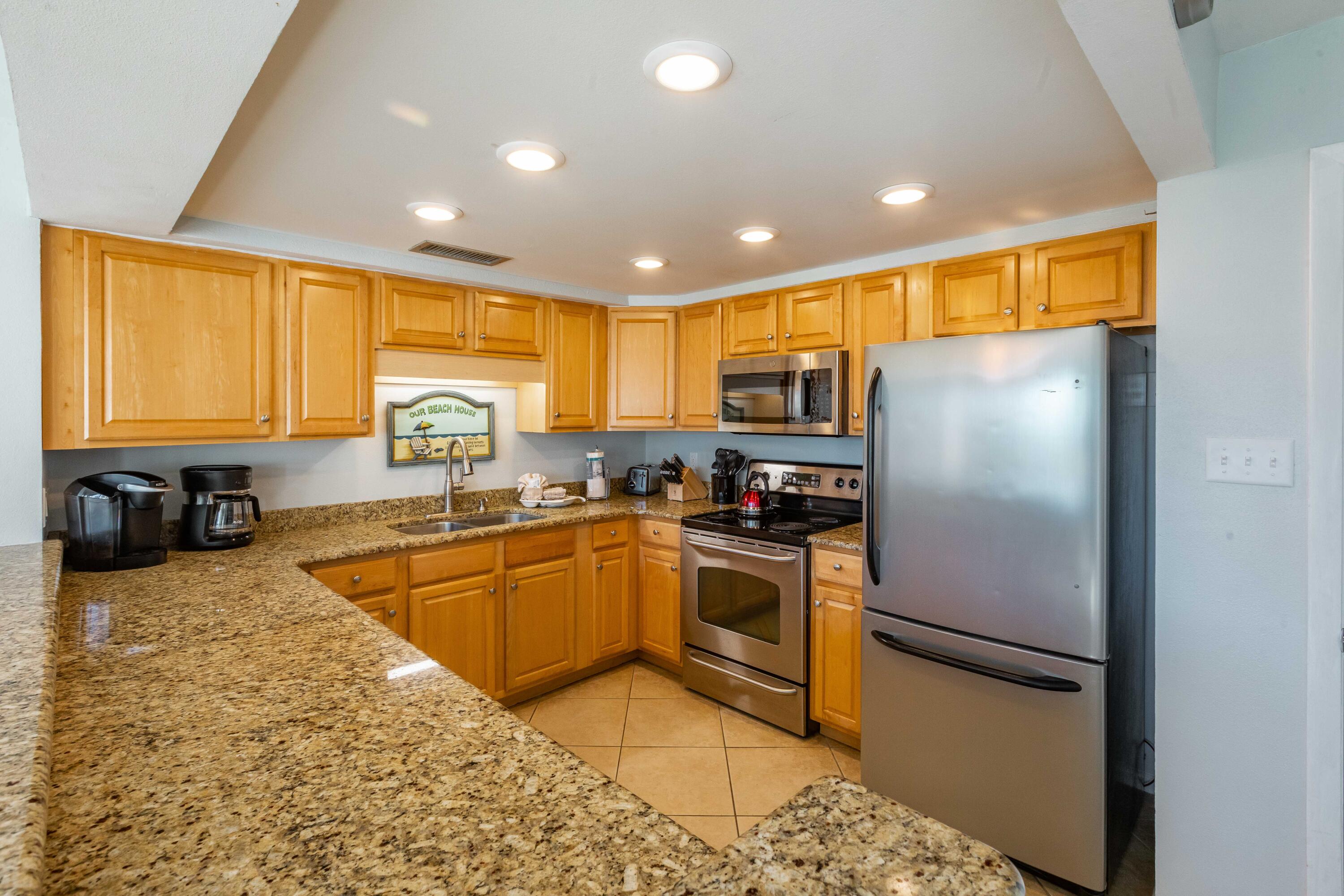 1030 East E Highway, Unit 25 Destin, FL 32541 - Photo 7 of 34 a kitchen with granite countertop a refrigerator a sink dishwasher stove top oven and cabinets
