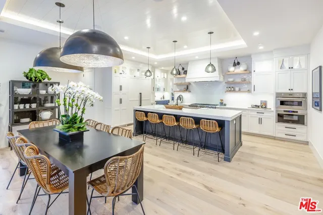 a dining room with stainless steel appliances kitchen island granite countertop a table chairs and a refrigerator