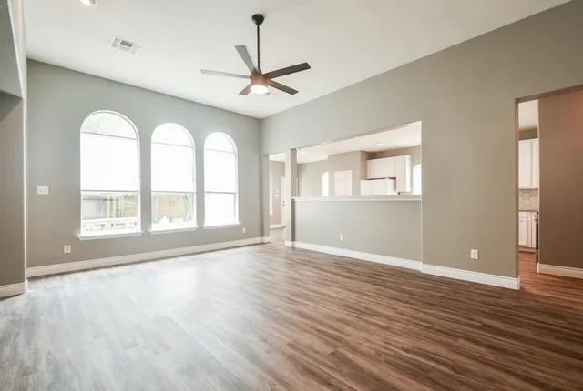 a view of an empty room with wooden floor and a window