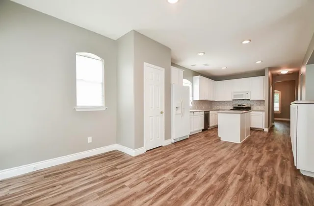 a kitchen with stainless steel appliances refrigerator wooden floor and window