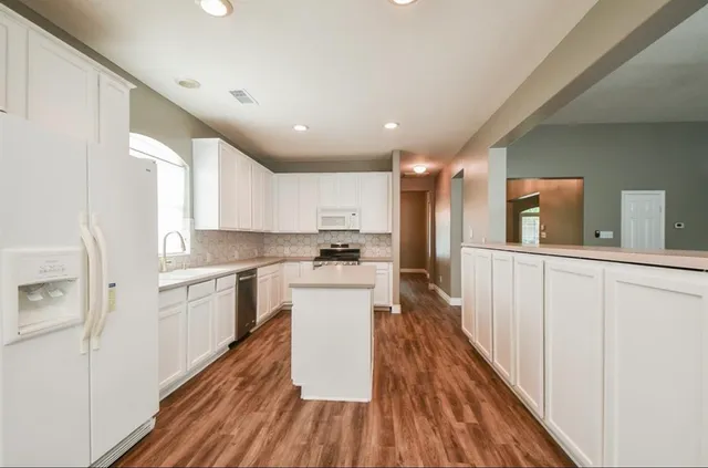 a kitchen with white cabinets and stainless steel appliances