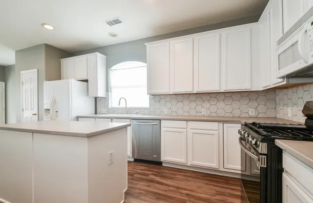 a kitchen with stainless steel appliances granite countertop a sink and cabinets with wooden floor