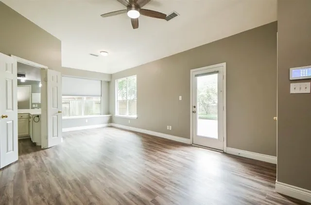 a view of an empty room with a window and wooden floor