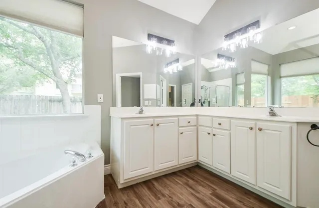a spacious bathroom with a double vanity sink a mirror and a bathtub