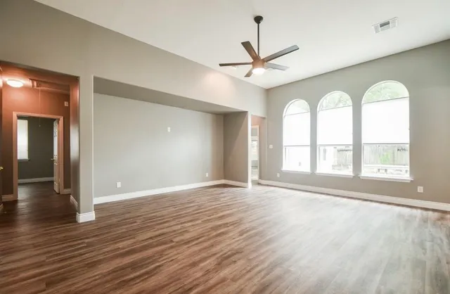 a view of empty room with wooden floor and fan