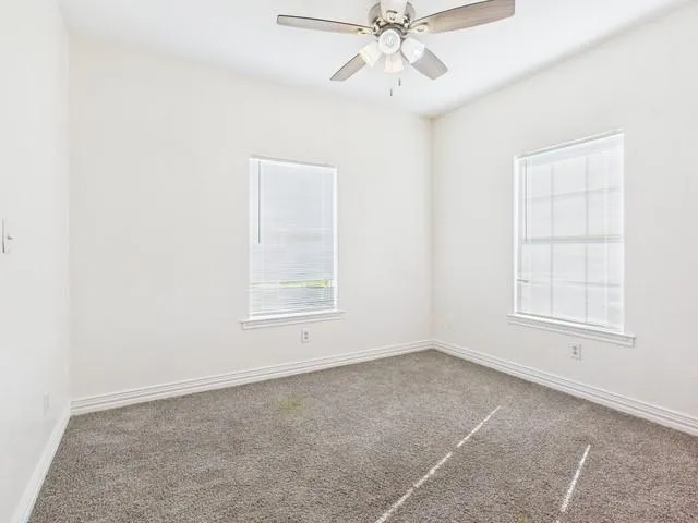 an empty room with windows and fan