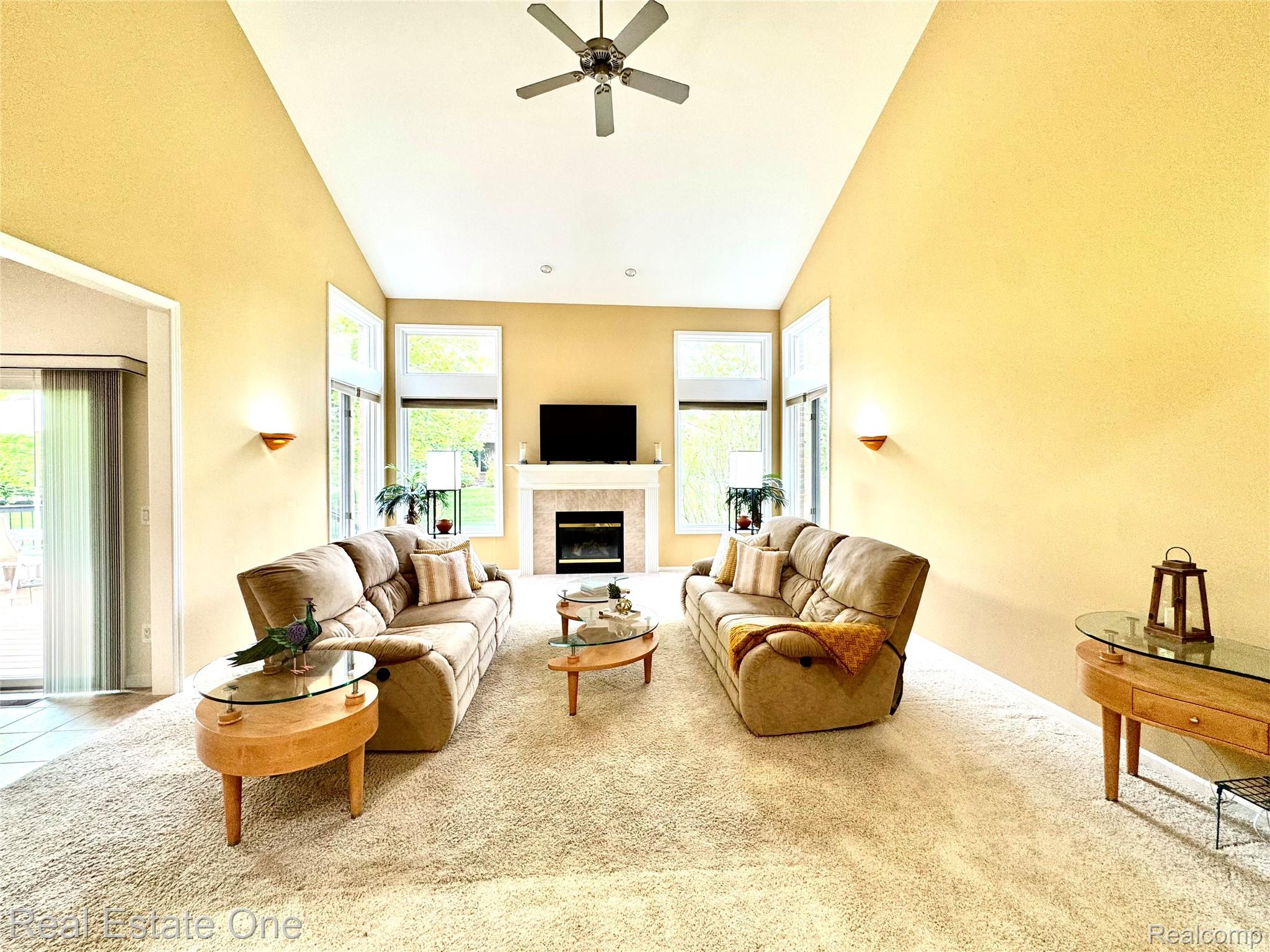 1215 Letica Drive Rochester, MI 48307 - Photo 43 of 43 Living room featuring a ceiling fan, light carpet, vaulted ceiling, and a tile fireplace