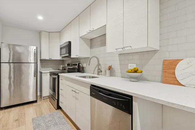 a kitchen with stainless steel appliances granite countertop a sink a refrigerator and a stove