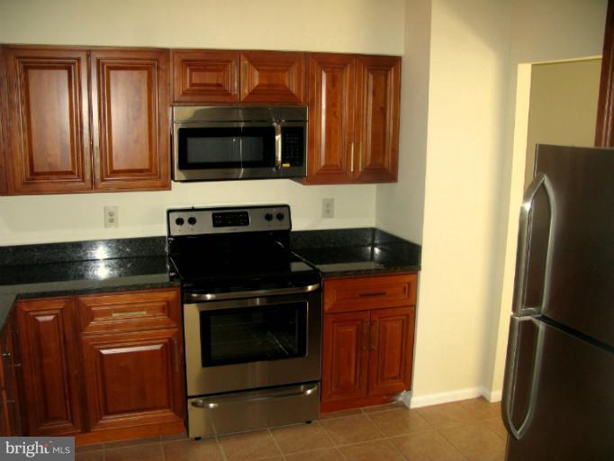 5618 Westgate Road Lanham, MD 20706 - Photo 13 of 17 a kitchen with stainless steel appliances wooden cabinets and a stove top oven