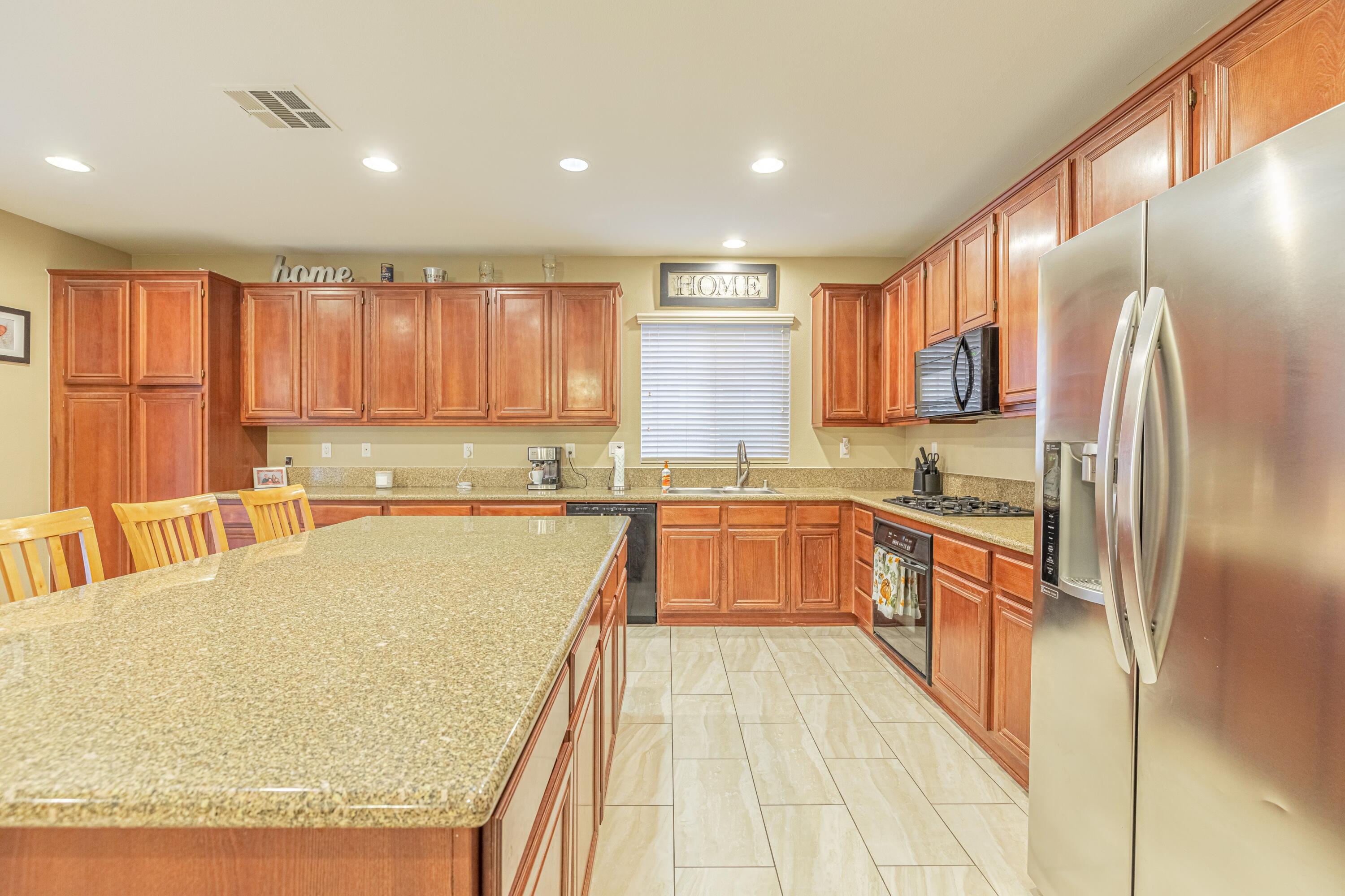 4403 Edam Street Lancaster, CA 93536 - Photo 18 of 42 a large kitchen with kitchen island granite countertop a large counter top stainless steel appliances and cabinets