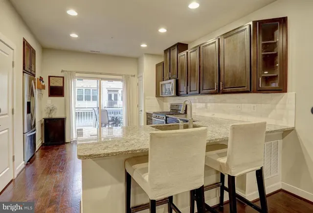 a view of a kitchen with stainless steel appliances granite countertop a stove top oven a chimney the cabinets and wooden floor