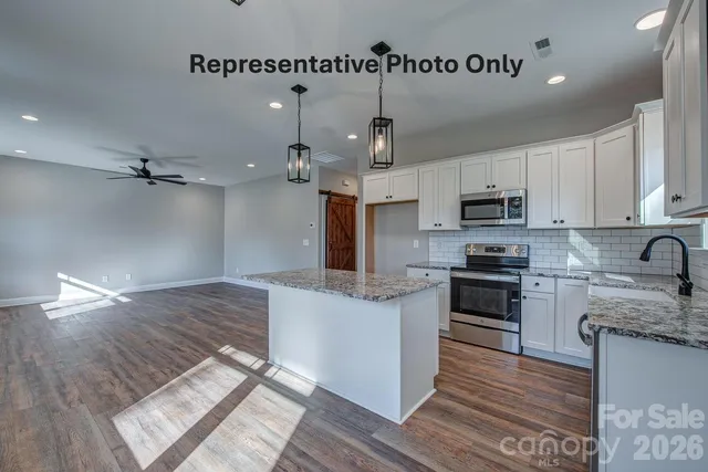 a kitchen with kitchen island granite countertop a sink cabinets and stainless steel appliances