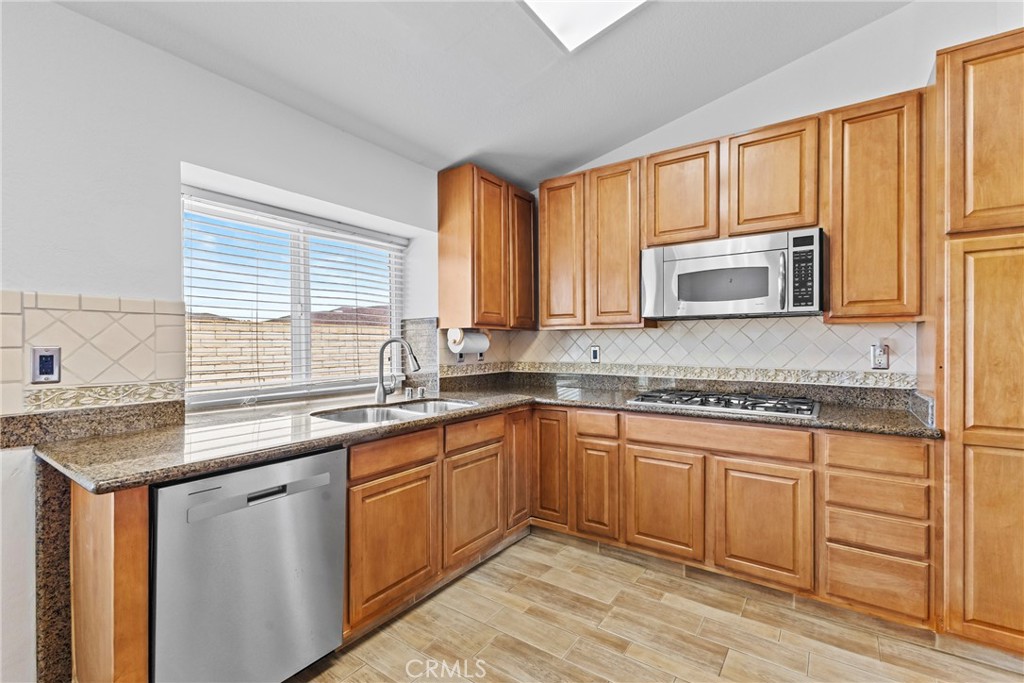 27126 Rio Vista Drive Menifee, CA 92586 - Photo 18 of 47 a kitchen with stainless steel appliances granite countertop wooden cabinets a sink and dishwasher with wooden floor