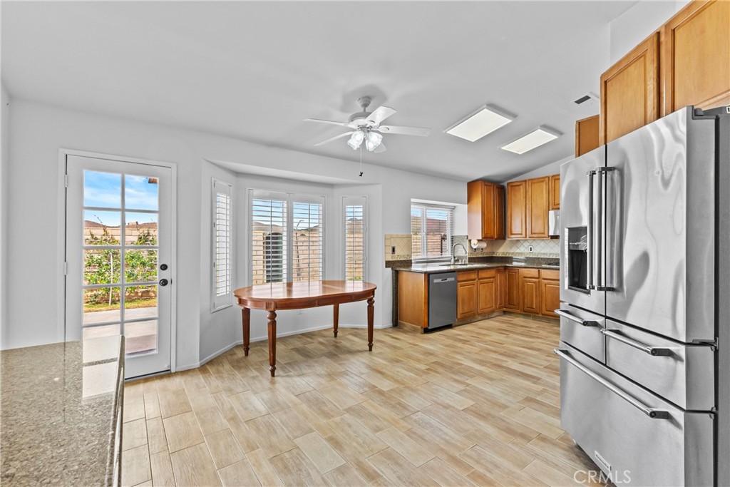 27126 Rio Vista Drive Menifee, CA 92586 - Photo 19 of 47 a kitchen with stainless steel appliances a refrigerator a stove a sink dishwasher and a dining table with wooden floor