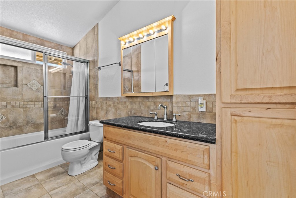 27126 Rio Vista Drive Menifee, CA 92586 - Photo 25 of 47 a bathroom with a granite countertop sink a toilet a mirror and shower
