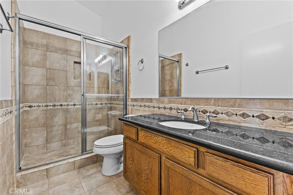 27126 Rio Vista Drive Menifee, CA 92586 - Photo 27 of 47 a bathroom with a granite countertop sink a toilet a mirror and shower