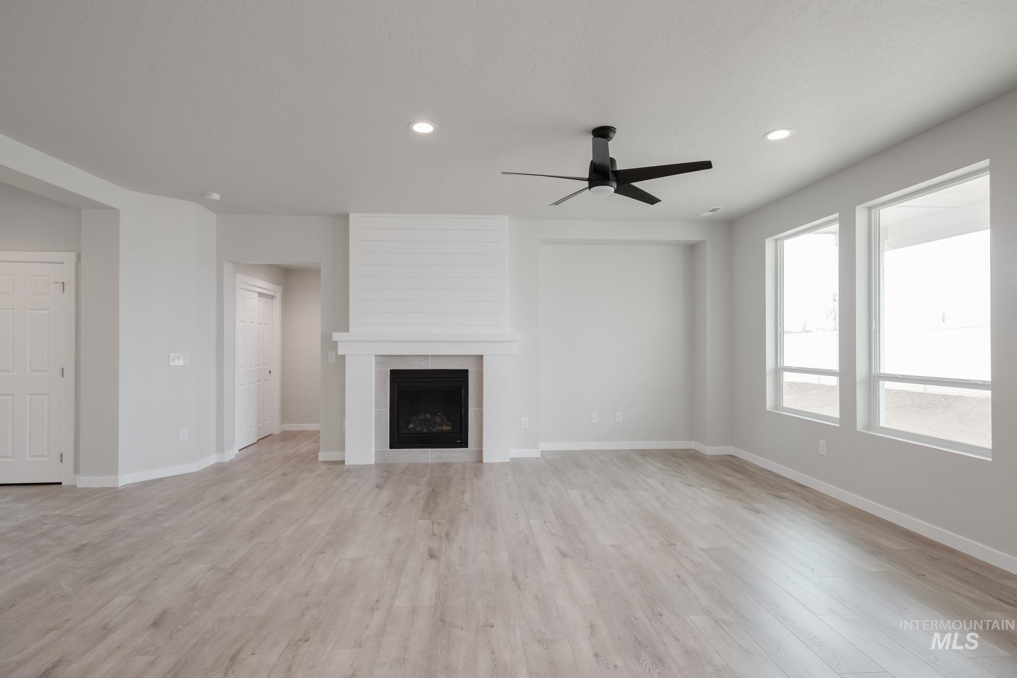 5261 South Memory Avenue Meridian, ID 83642 - Photo 10 of 30 Unfurnished living room with recessed lighting, a ceiling fan, a fireplace, and light wood-style flooring