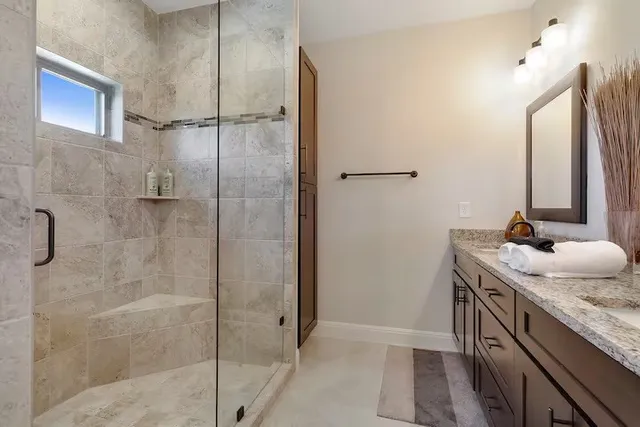 a bathroom with a granite countertop sink a mirror and shower