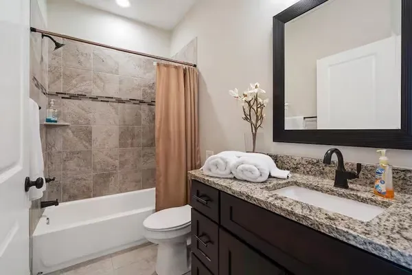 a bathroom with a granite countertop sink a toilet and shower