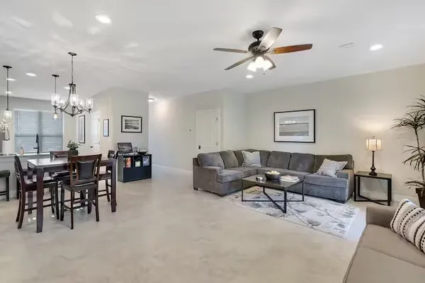 a living room with furniture a chandelier fan and a window