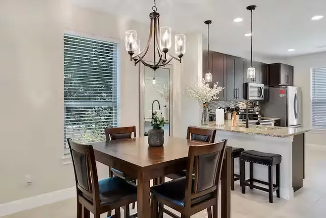 a kitchen with stainless steel appliances a dining table chairs and refrigerator