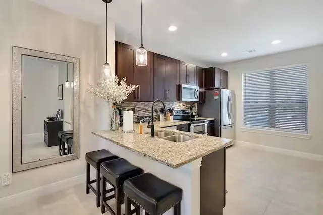 a kitchen with kitchen island granite countertop a sink and refrigerator
