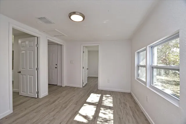 an empty room with wooden floor and windows