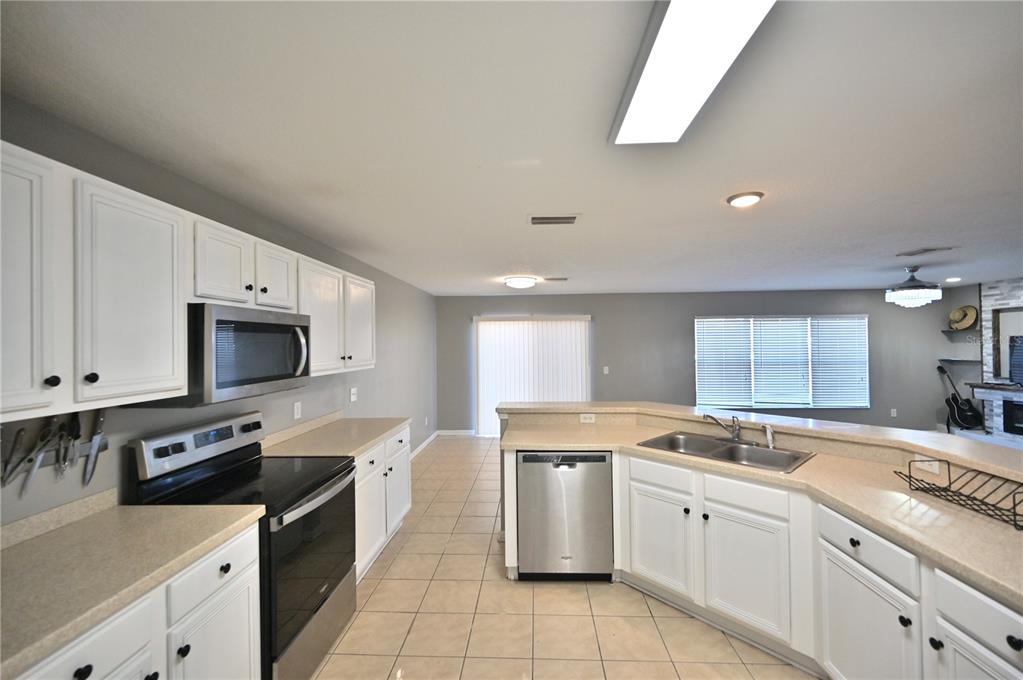 10922 Subtle Trail Drive Riverview, FL 33579 - Photo 37 of 60 a kitchen with granite countertop a sink a stove a microwave a counter space and cabinets