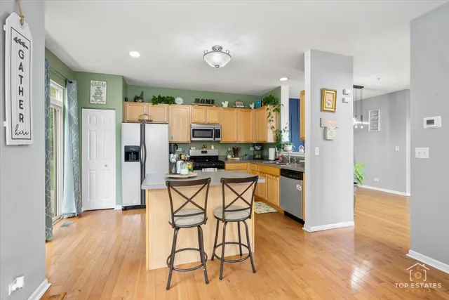 a kitchen with stainless steel appliances kitchen island granite countertop a refrigerator a stove a microwave oven with white cabinets and wooden floor