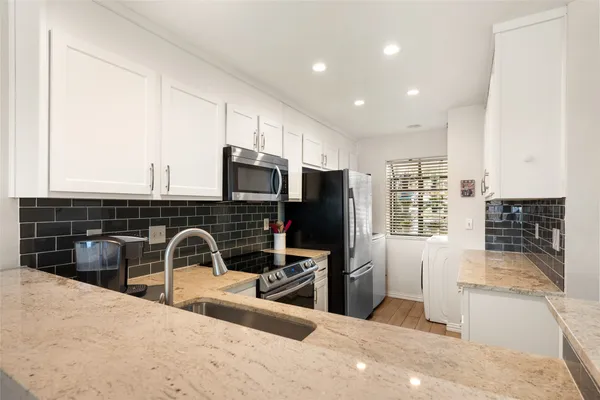 a kitchen with stainless steel appliances kitchen island granite countertop a stove a sink a refrigerator and blue cabinets with wooden floor