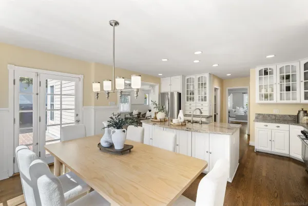 a kitchen with a dining table chairs and white cabinets