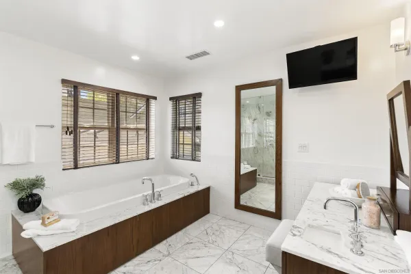 a bathroom with a tub a sink and a large mirror